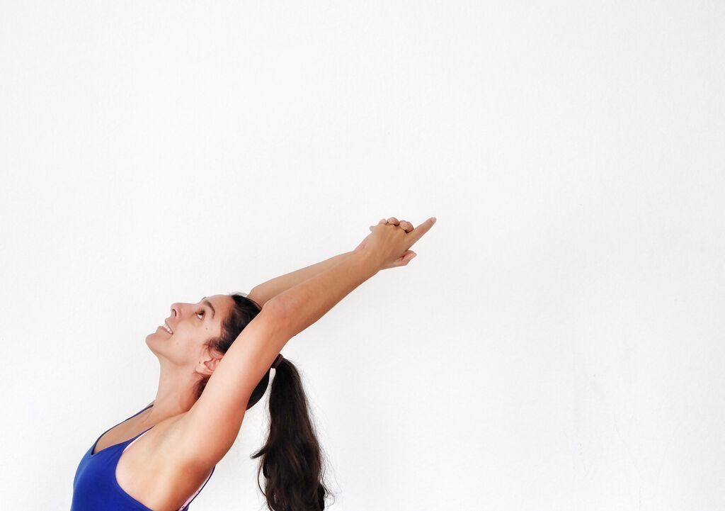 Maya, smiling as she raises her arms and gave overhead into a backbend.